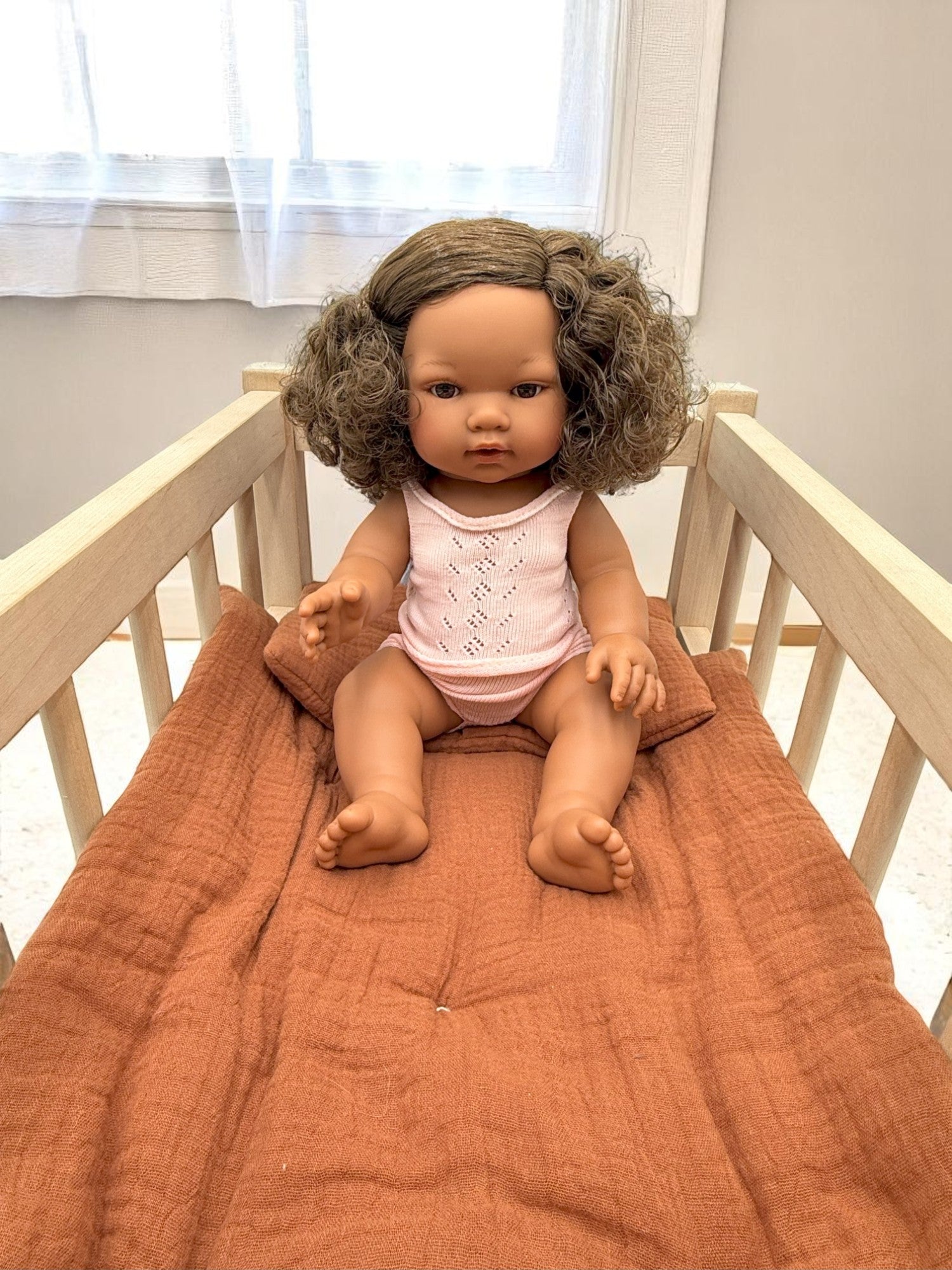 Lifelike Havana baby doll celebrating natural curls and diverse representation in pink pajama set
