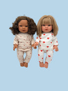 Two dolls wearing matching pajamas with red hearts on a white background