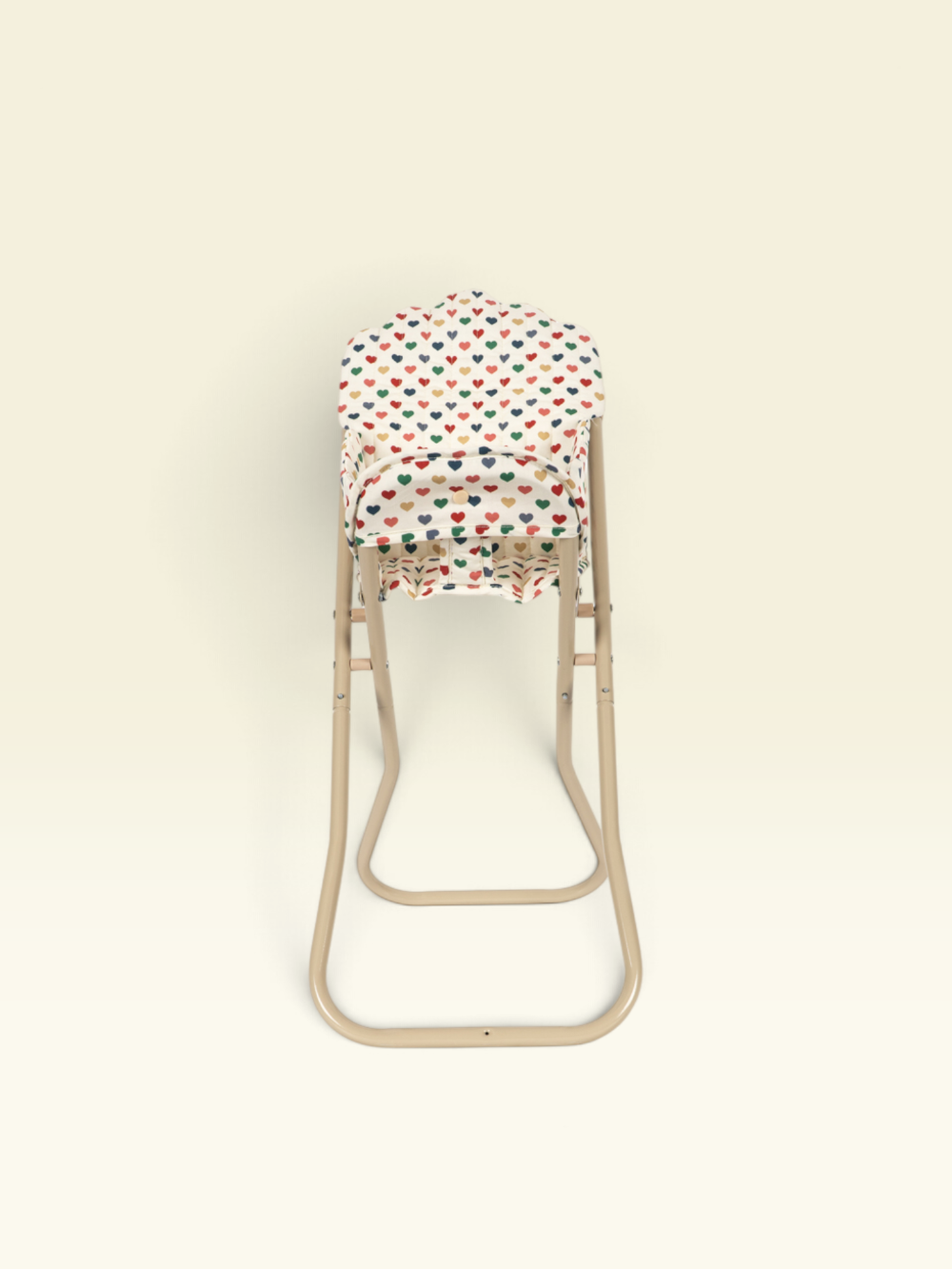 A baby carrier seat insert with a colorful heart pattern, shown on a beige metal high chair against a solid cream background.