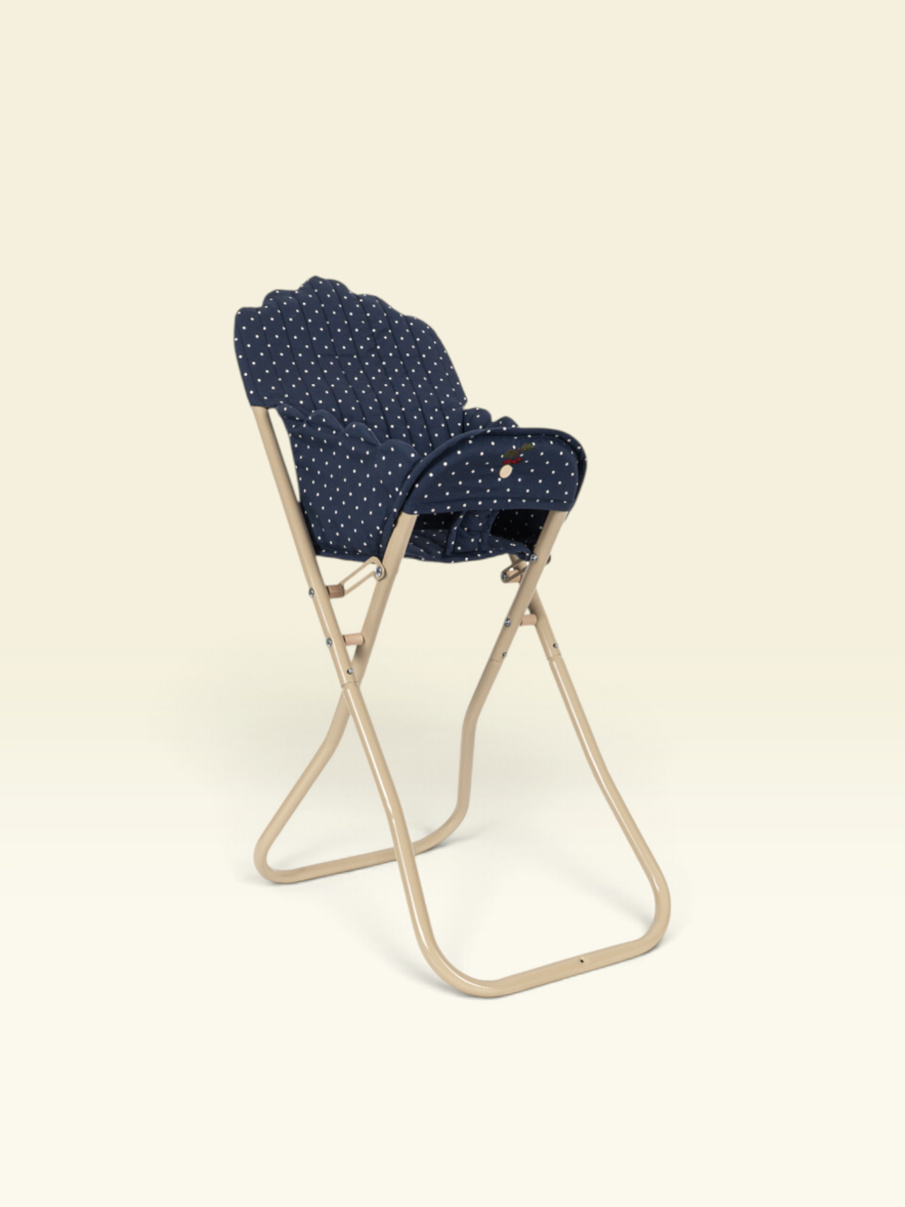 A navy blue fabric chair cushion with small white polka dots, shown on a beige folding chair against a solid cream background.