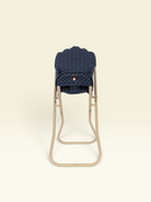A baby stroller seat insert with a navy blue and white polka dot pattern, shown on a beige metal stroller frame against a solid cream background.