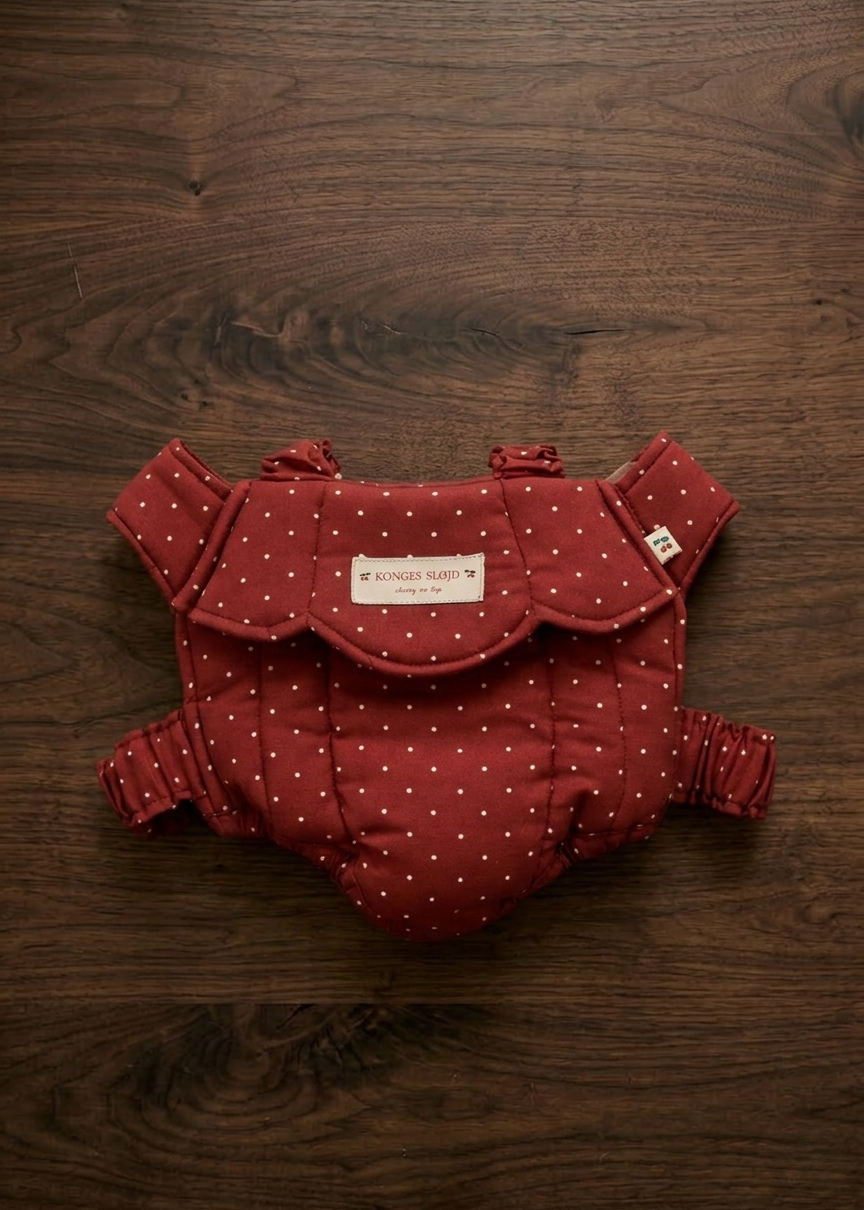 Konges Sløjd baby doll carrier in Fraise Dot berry red polka dot print laid flat on white background