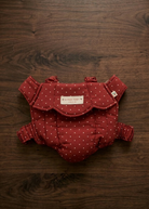 Konges Sløjd baby doll carrier in Fraise Dot berry red polka dot print laid flat on white background