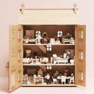 Detailed dollhouse with miniature furniture and accessories on a plain background