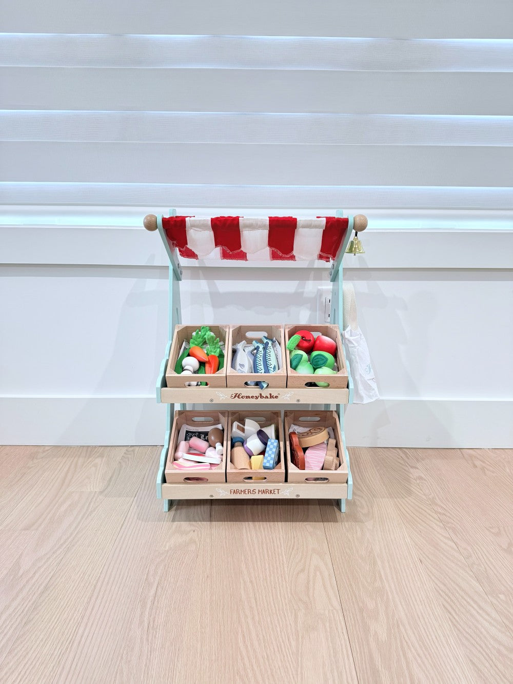 Wooden market stall with striped canopy on a wooden floor.