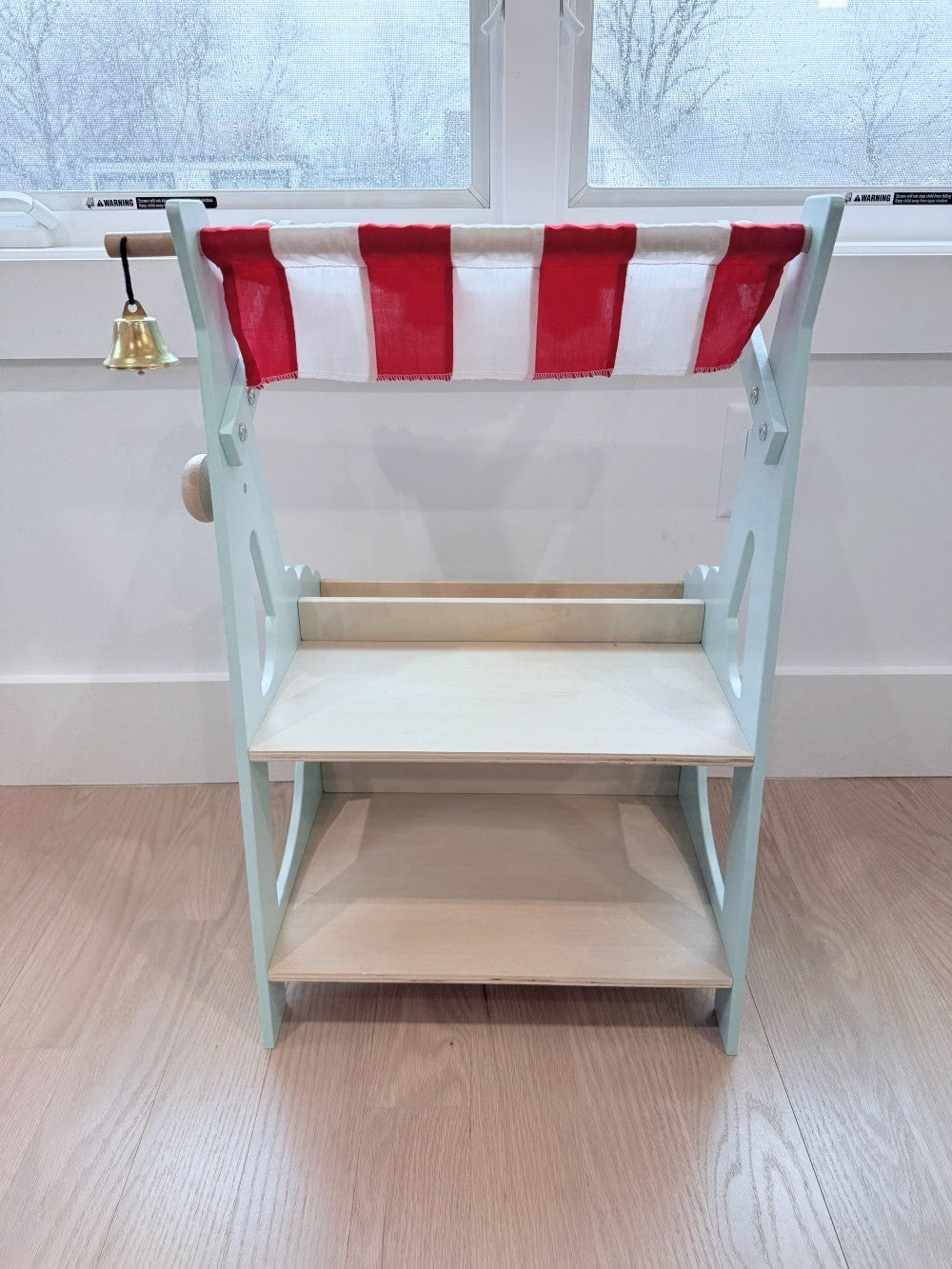 Market stall with a red and white striped canopy on a wooden floor.