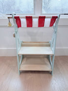 Market stall with a red and white striped canopy on a wooden floor.