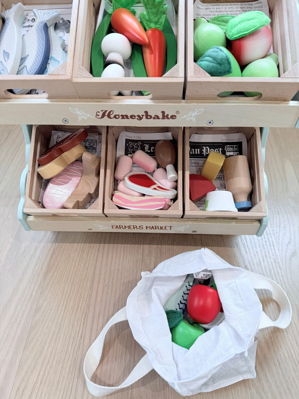 Wooden toy set with vegetables and fruits in a 'Honeybake' box on a light wooden surface.