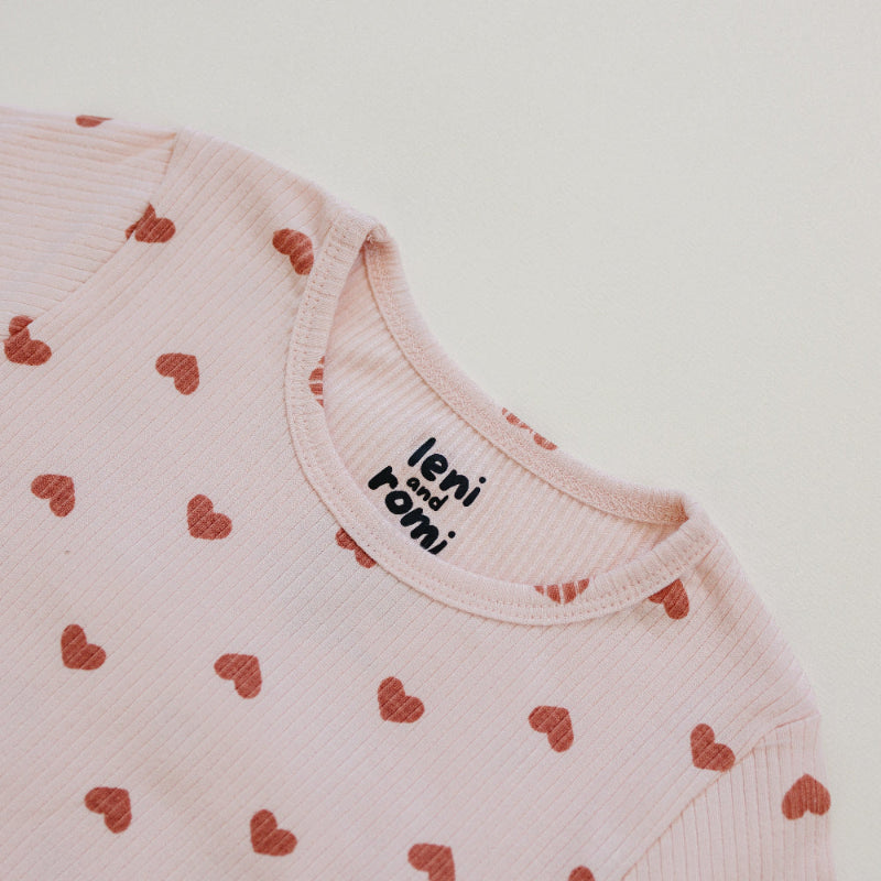 Detail of Leni & Romi tagless ribbed fabric with scattered mauve hearts design