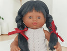 Doll with black hair in pigtails and a white outfit on a light background