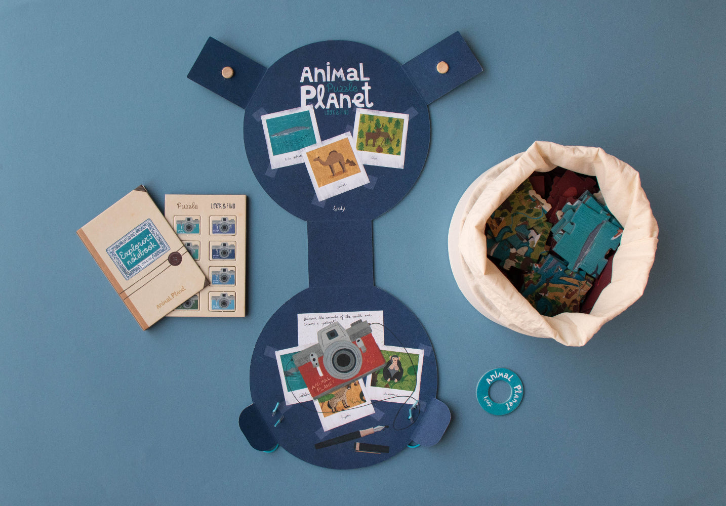 Collection of items including a blue board with 'Animal Planet' branding, photos, and a drawstring bag on a blue background.