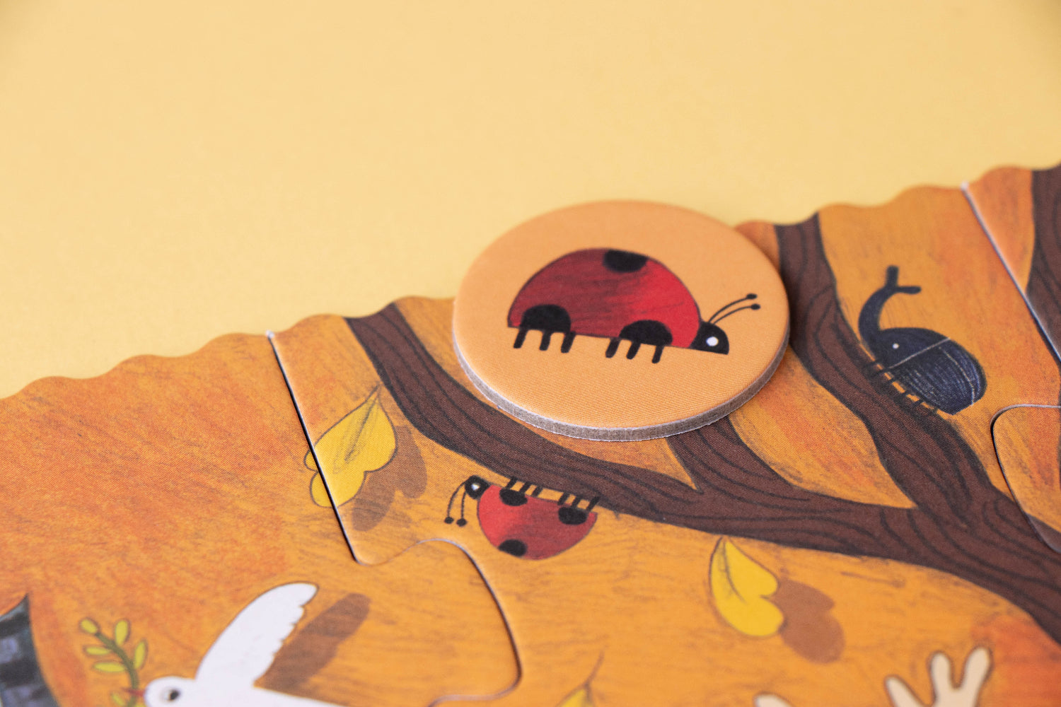 Wooden puzzle piece with a ladybug design on a yellow background