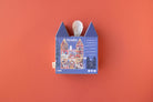 Blue house-shaped box with a white candle on an orange background