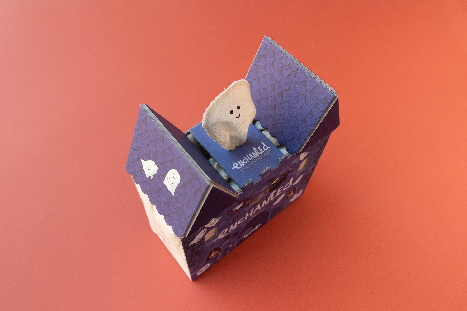 Small plush toy inside a purple box on an orange background