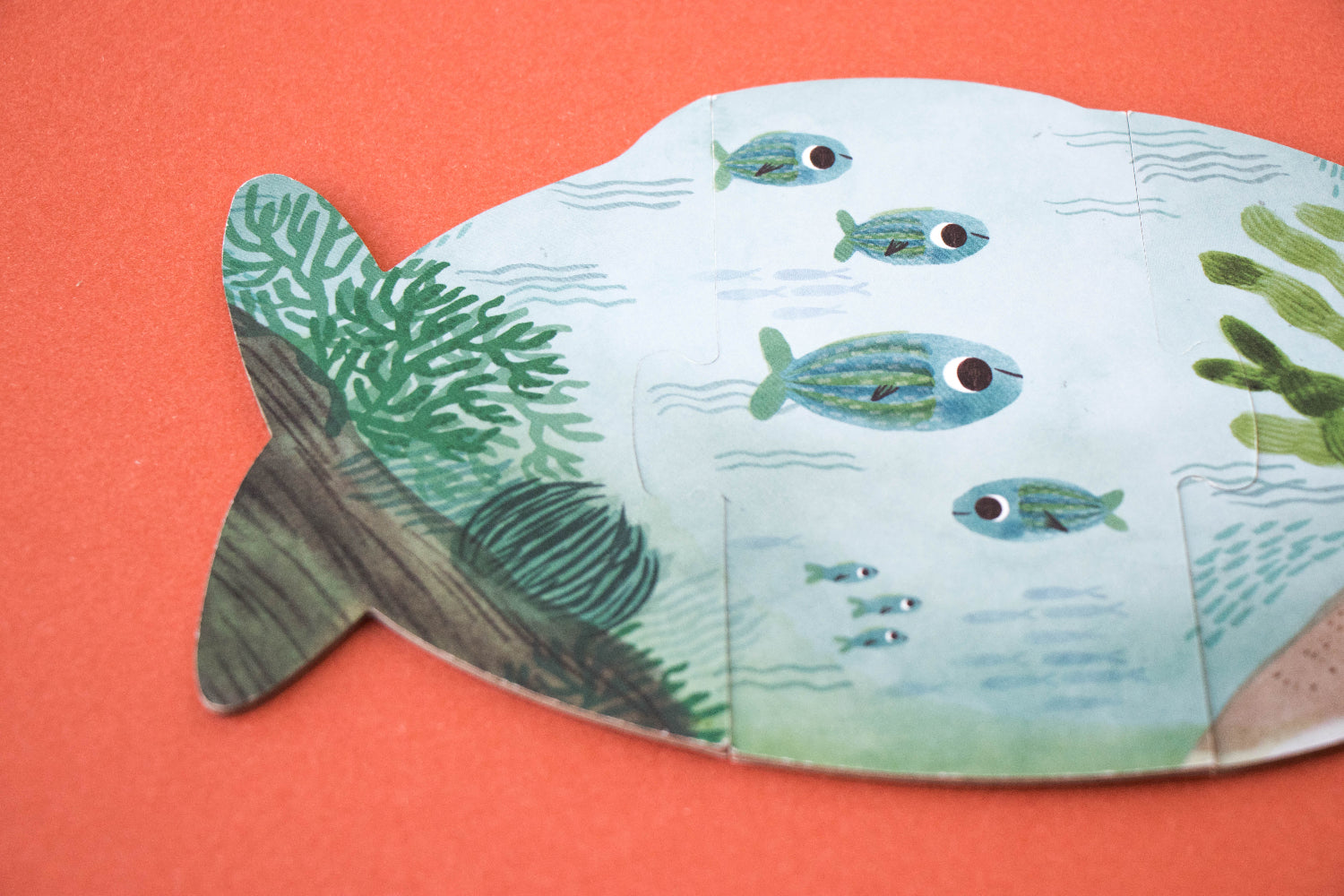 Fish-shaped puzzle with underwater scene on an orange background