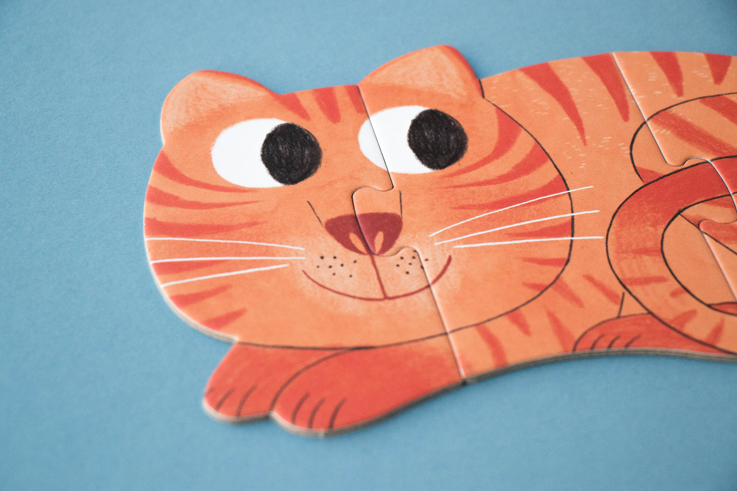 Cat-shaped paper puzzle on a blue background