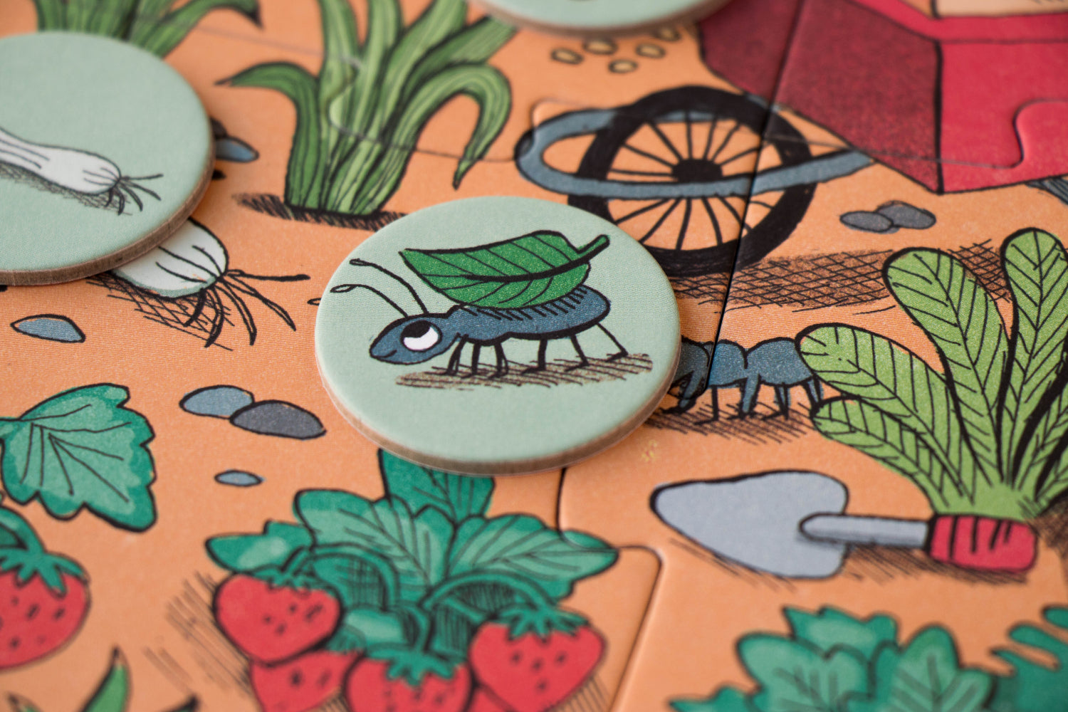 Close-up of a board game piece with a caterpillar design on a garden-themed board.