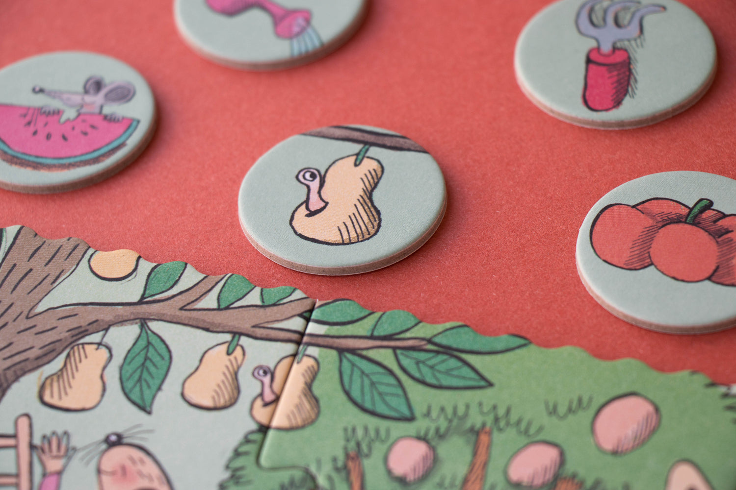 Round game pieces with cartoonish illustrations on a pink background
