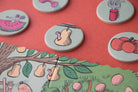 Round game pieces with cartoonish illustrations on a pink background
