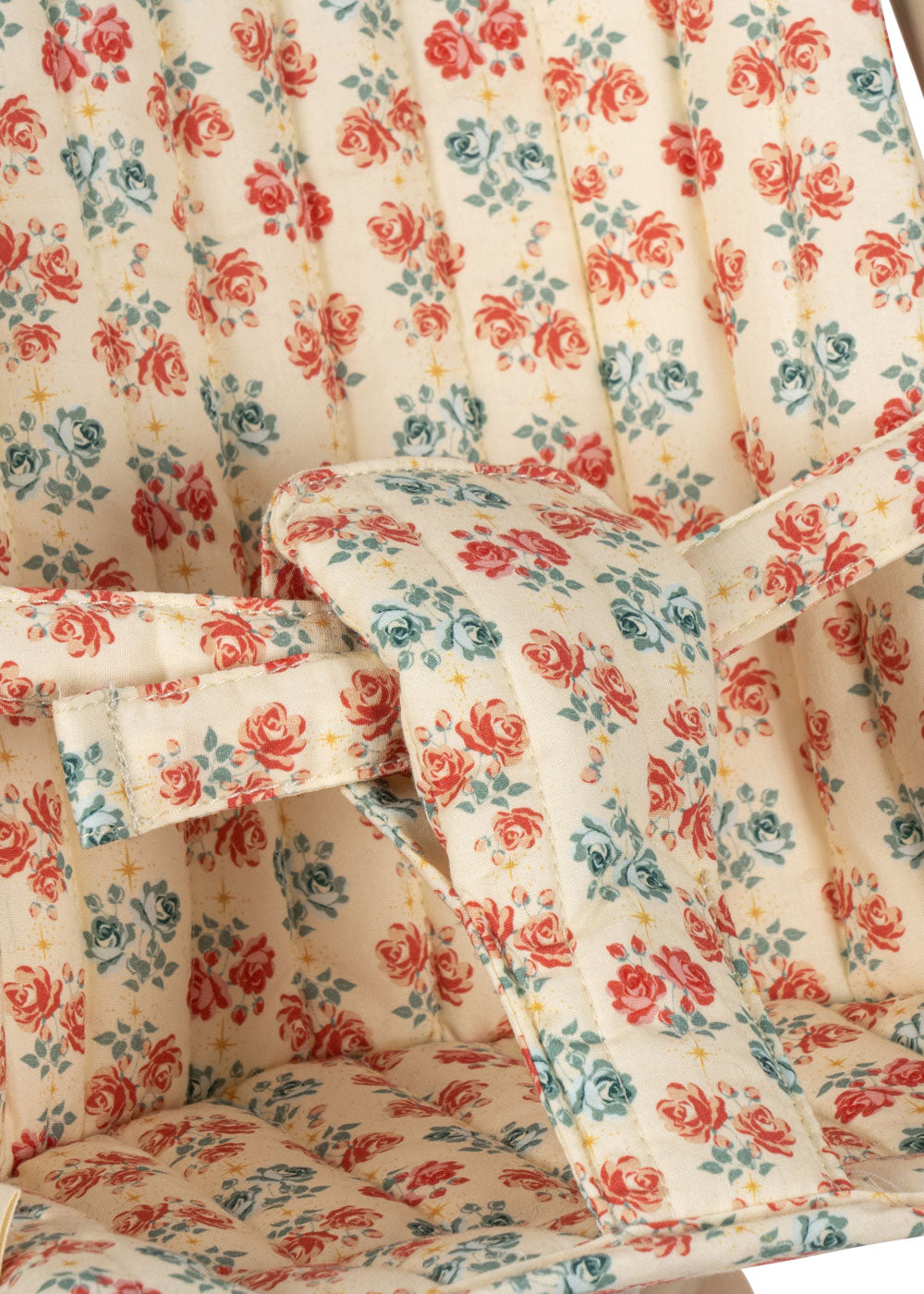 Close-up of coral and teal rose pattern fabric with safety harness on doll stroller seat