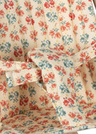 Close-up of coral and teal rose pattern fabric with safety harness on doll stroller seat