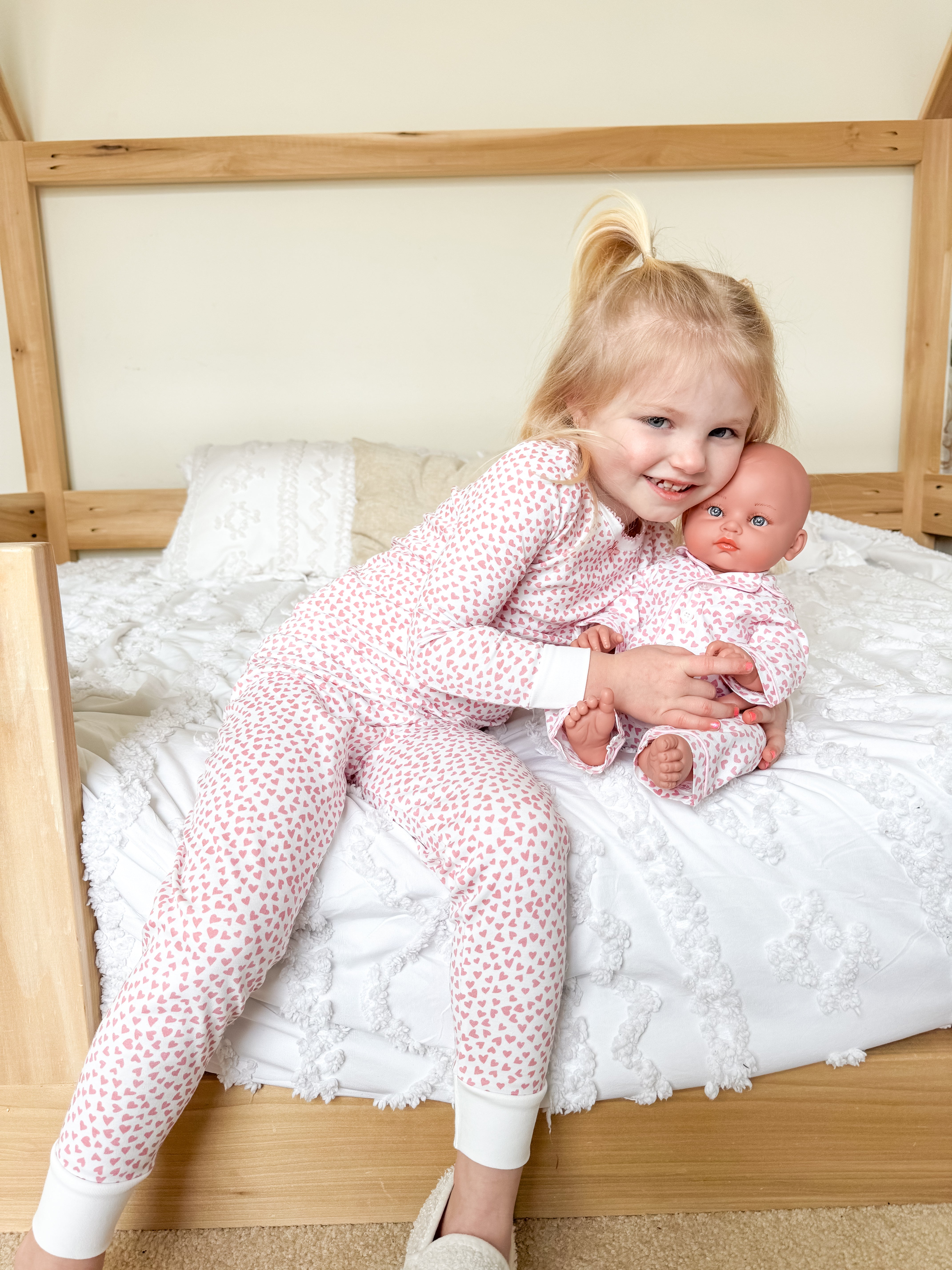 Girl hugging doll in pink pjs