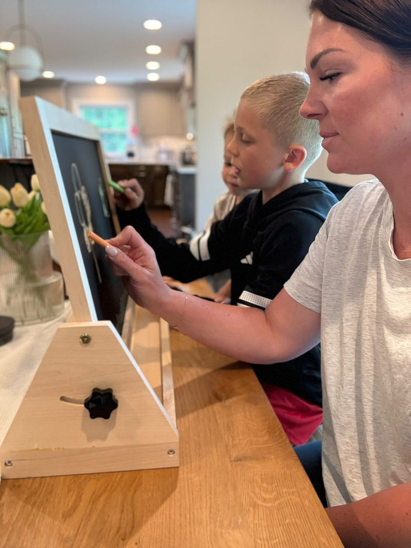Woman and child using a digital device on a wooden table in a home setting