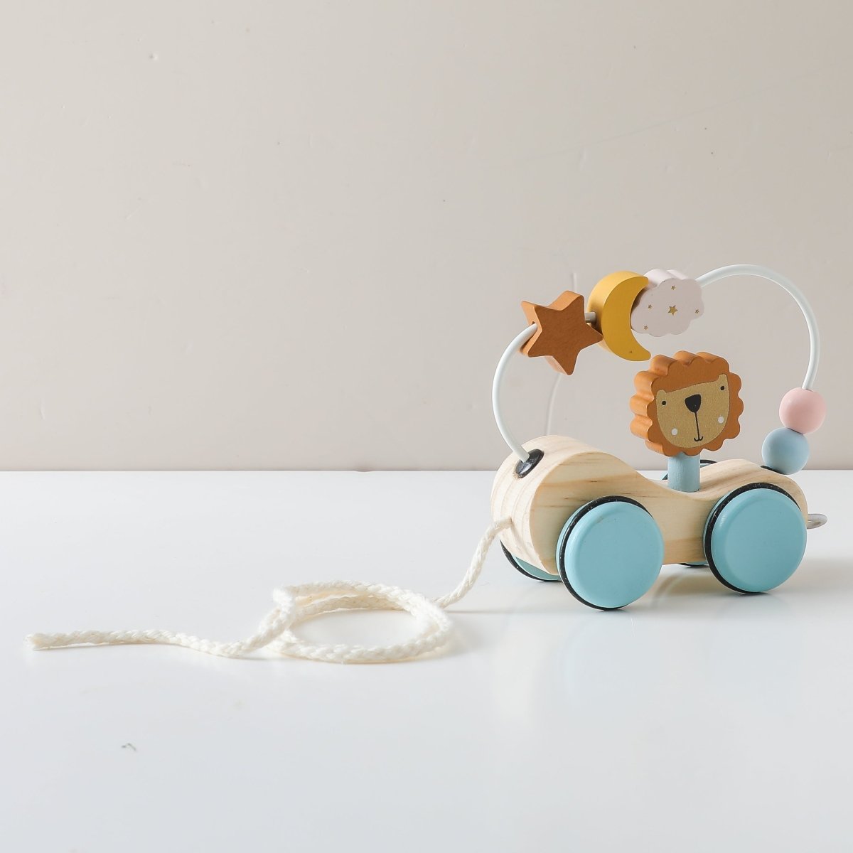 Wooden Montessori lion pull toy with natural finish and pastel blue wheels on hardwood floor