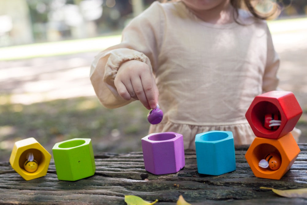 Child playing with colorful geometric shape sorting toys outdoors.