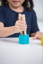 Child using wooden tongs to sort PlanToys colorful bees into hives