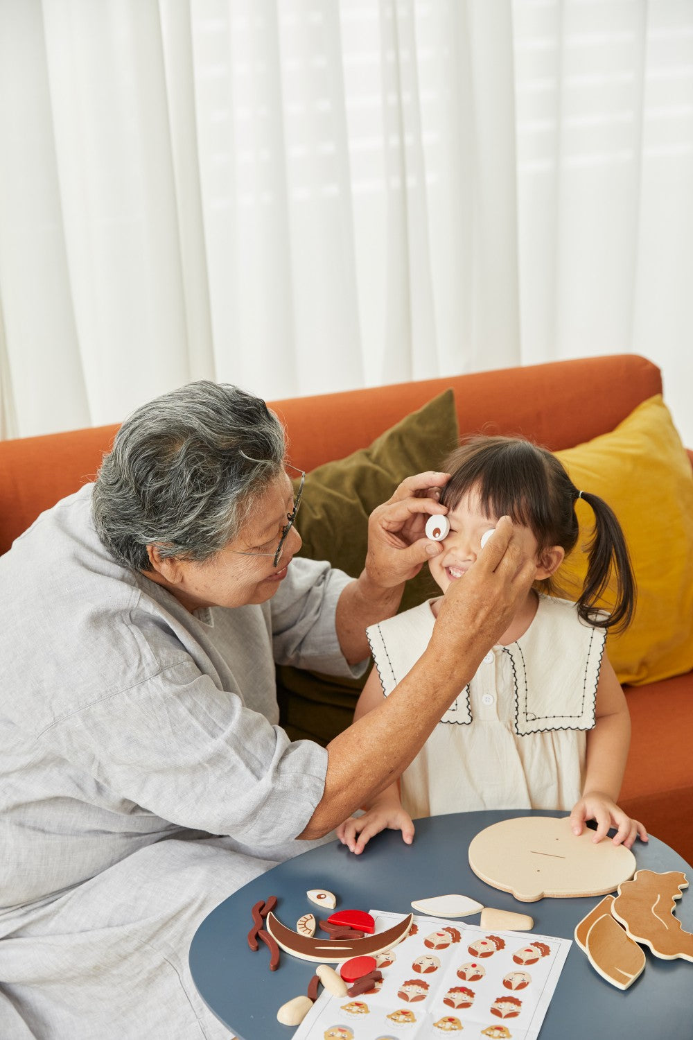 Grandmother and granddaughter playing with wooden toy on a table.
