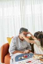 Grandparent and granddaughter playing a game together on a couch.