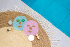 Two colorful face masks on a textured mat with a blue and gray background