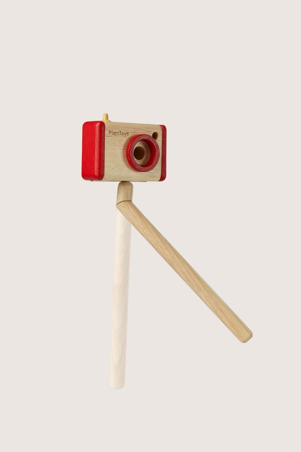Wooden toy camera with red top and beige stand on a light gray background