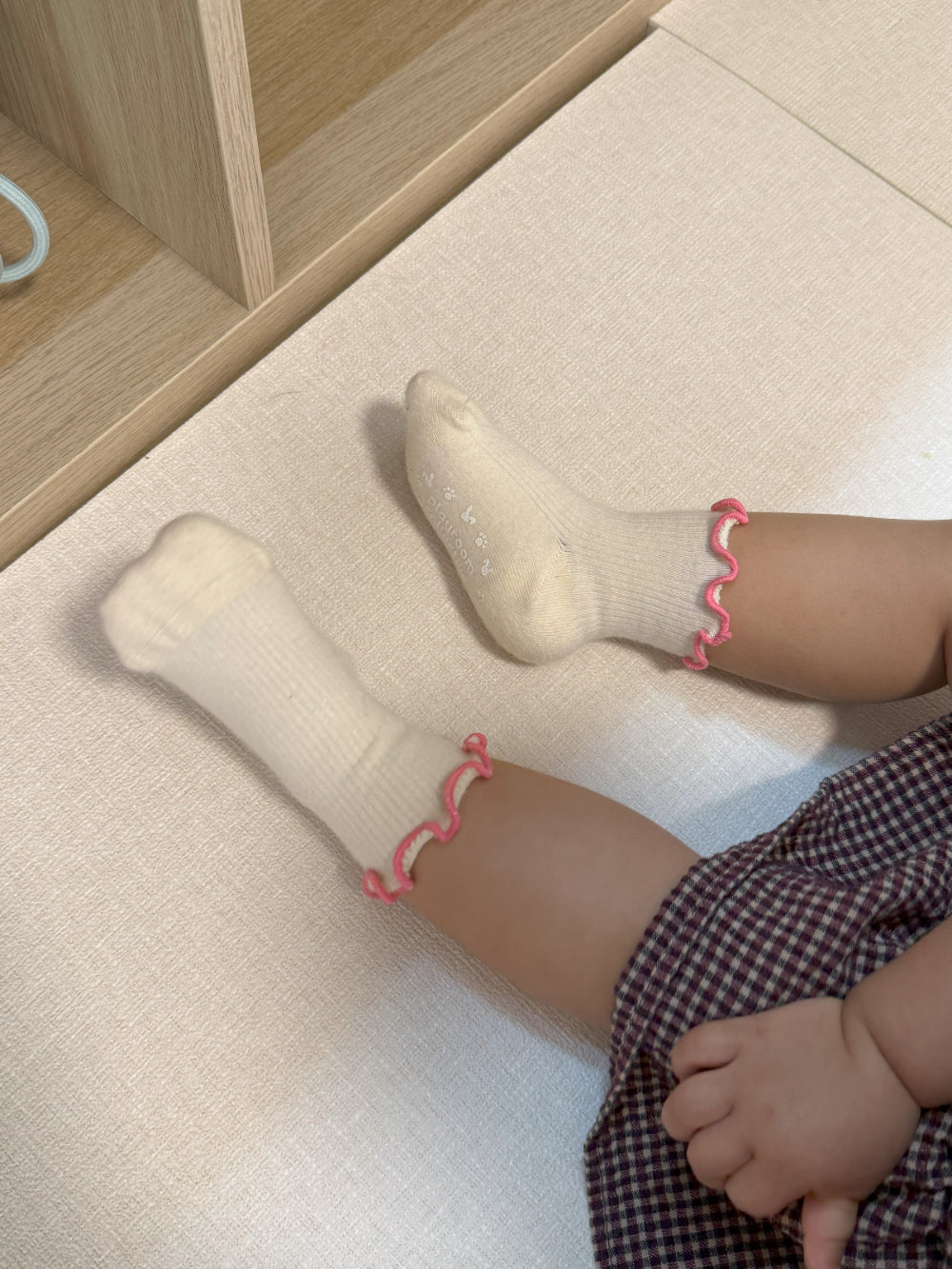 Child in cozy ruffle socks sitting cross-legged during indoor playtime