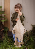 Young children holding cream Senger goose companions outdoors during imaginative play