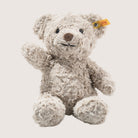 Plush teddy bear with a yellow tag on a light background