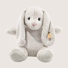 Plush toy rabbit with a visible brand tag on a light gray background