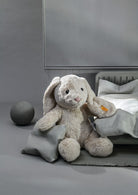 Plush bunny toy on a bed with a gray background