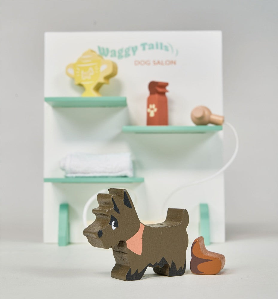 Wooden dog toy in front of a miniature dog salon set on a white background