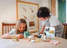 Two children playing with toys at a table in a room with a poster on the wall.