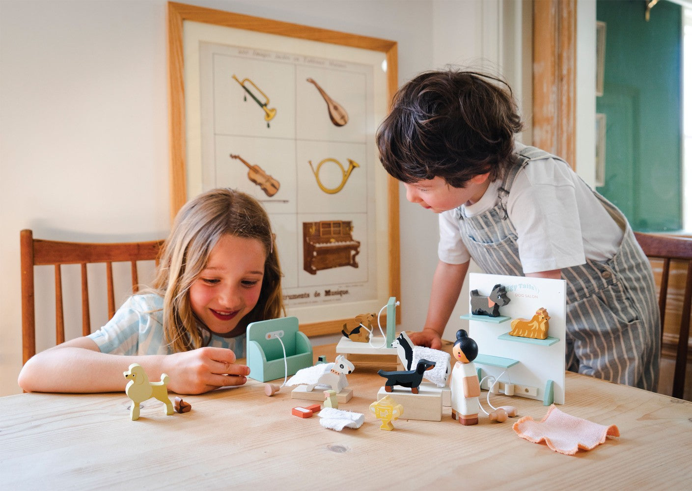 Two children playing with toys at a table in a room with a poster on the wall.