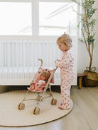 Child playing with a doll in a stroller in a nursery