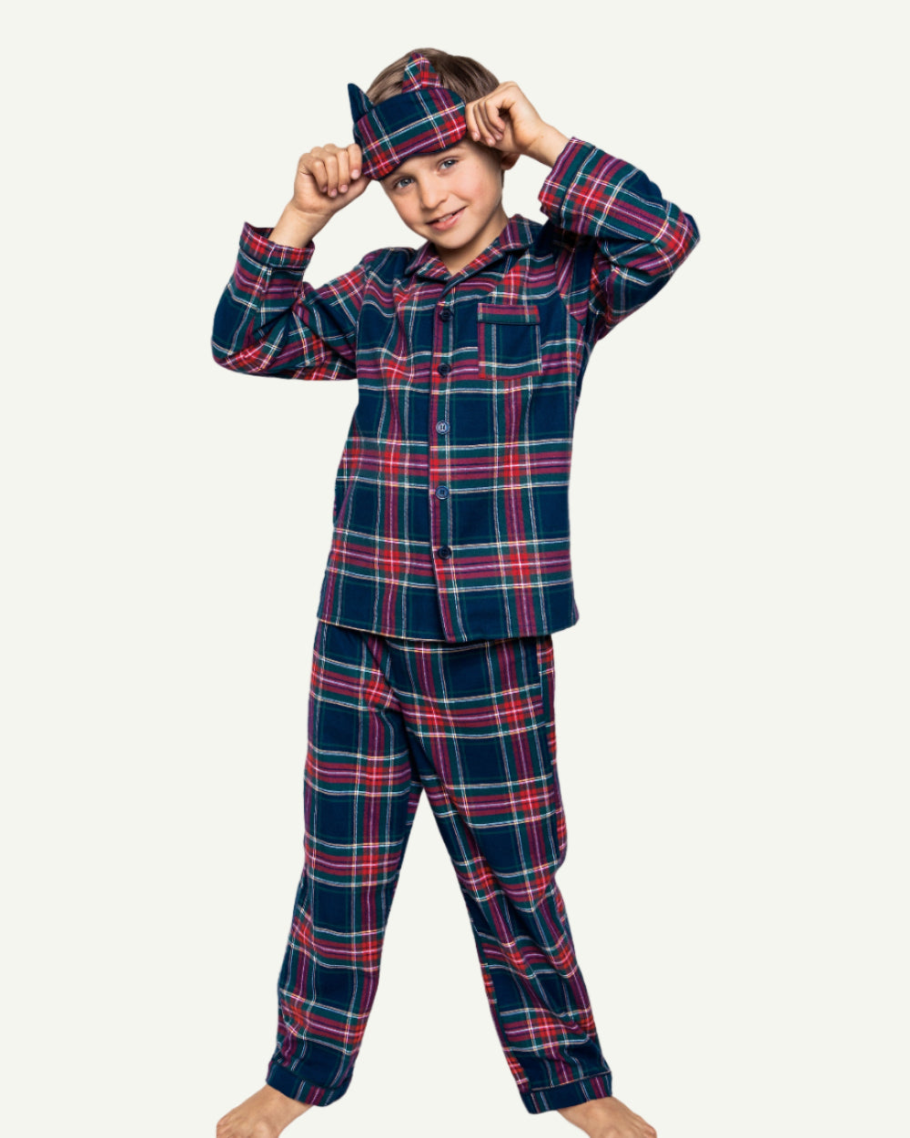 Child wearing Windsor Tartan pajamas in sophisticated navy plaid with coordinating sleep mask