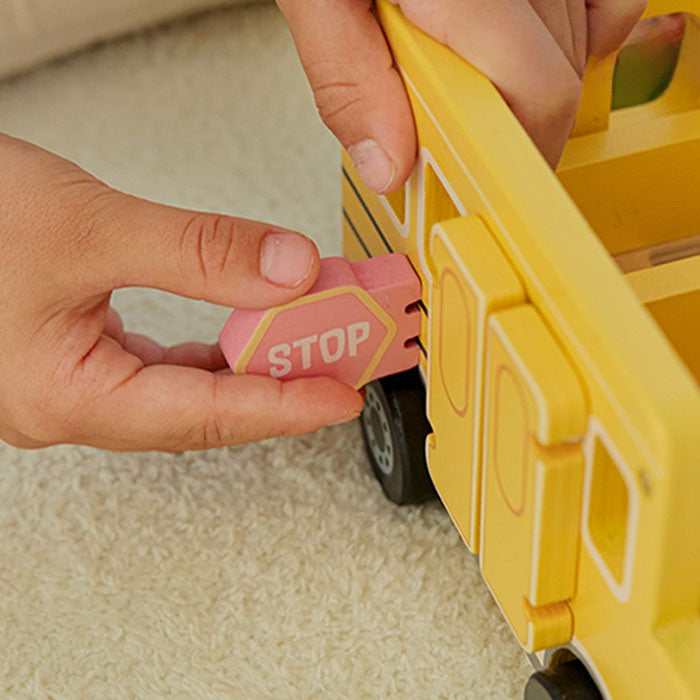 Child's hand placing wooden character figure on carpet showing figures sized for small hands