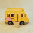 Close-up detail of smooth rounded wood edges and hand-painted pink stop sign on yellow school bus