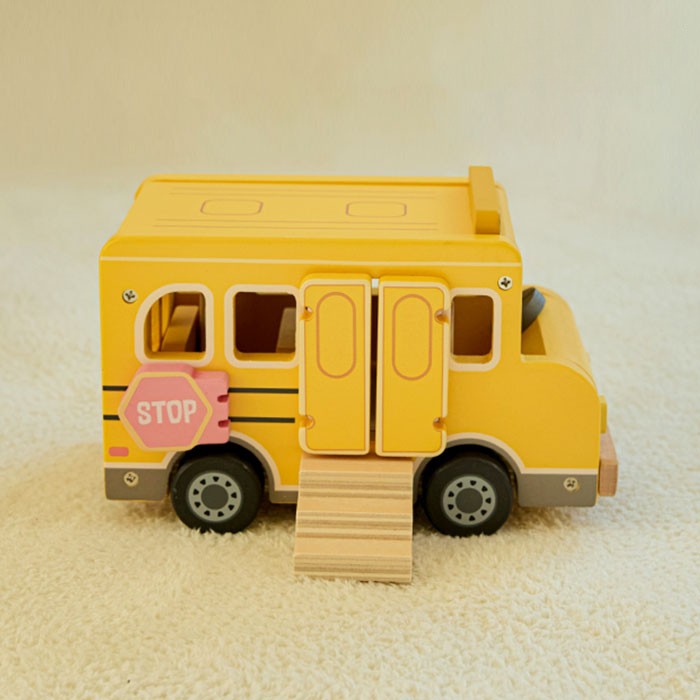 Close-up detail of smooth rounded wood edges and hand-painted pink stop sign on yellow school bus
