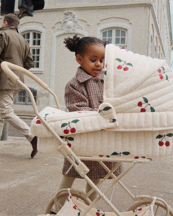 Sweet cream and cherry pattern doll pram with four spoked wheels and nostalgic quilted fabric details