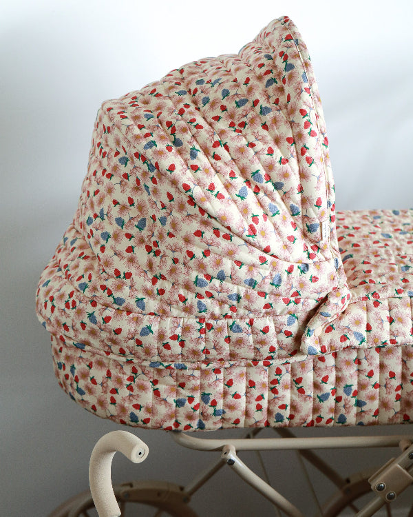 Whimsical cream and wildflower pattern doll pram with four spoked wheels and cheerful quilted fabric details