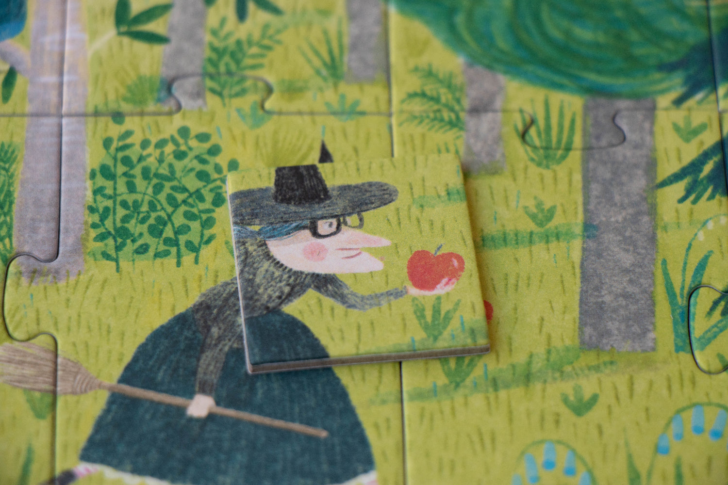 Wooden puzzle piece with a witch holding an apple in a forest setting
